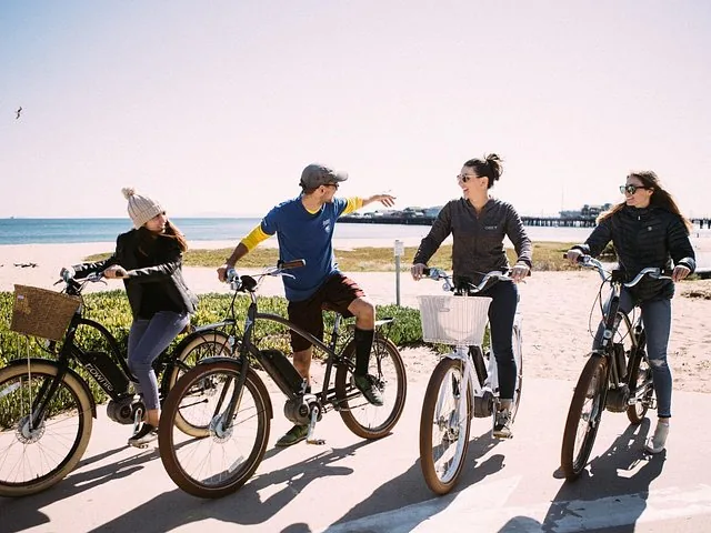Eine Gruppe von vier Personen auf E-Bikes macht eine Pause in Strandnähe.