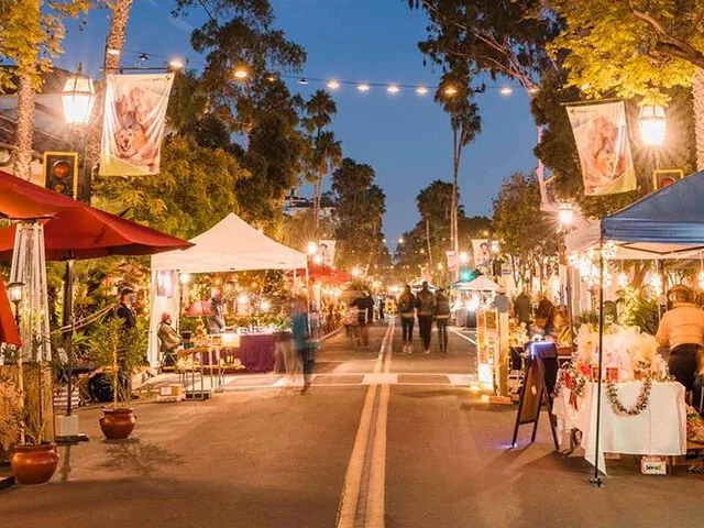 A vibrant evening street market lined with stalls and string lights.