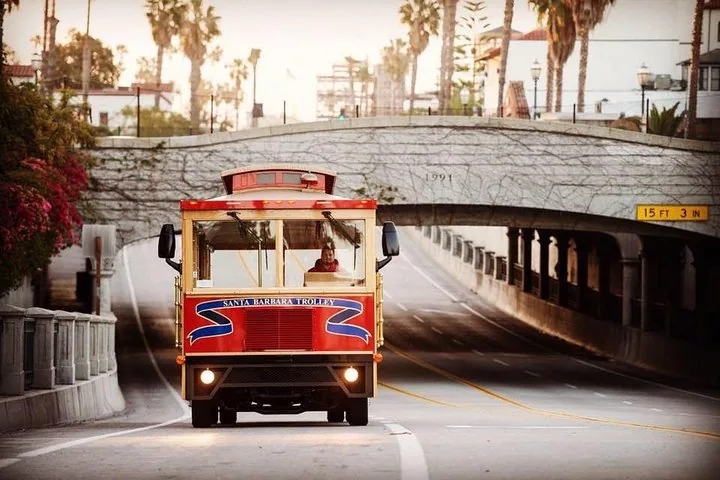 Roter Santa Barbara Trolley fährt unter einer Brücke hervor.